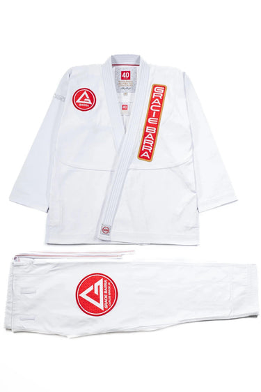40 Year Anniversary white BJJ kimono flat lay showing jacket and pants with Barra Shield, Gracie Barra Patch, and Legacy G detail