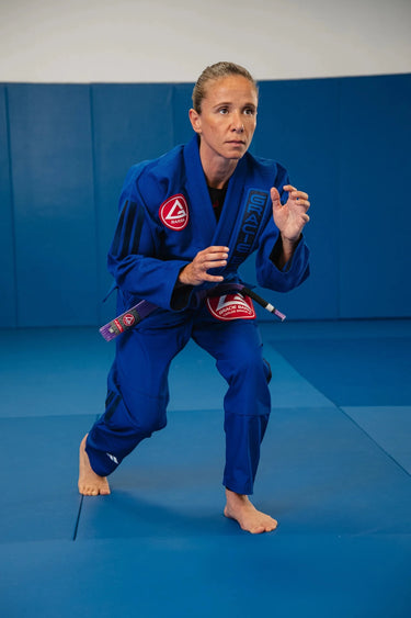 Womens blue Axis Kimono by adidas worn in a standing jiu-jitsu stance, showing the jacket sleeve and pant fit through the hips.