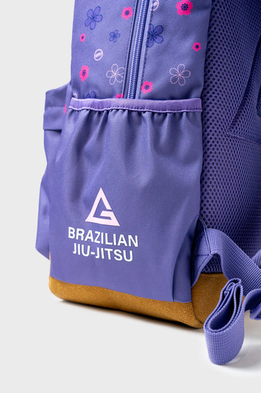Close-up of Purple Sakura Backpack side pocket showing floral pattern, Brazilian Jiu-Jitsu logo, and brown suede bottom panel
