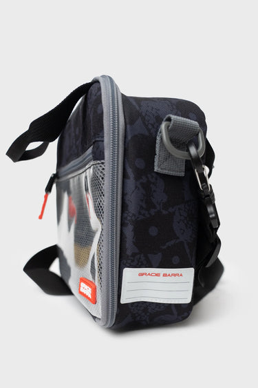Side of the black Barra Beachwalk lunchbox showing the clear zip pocket, red Gracie Barra rubber patch, writable name label, and shoulder strap clip.