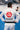 Back view of a practitioner wearing the white Ripstop Lightweight Kimono with a black belt on a blue gym mat, showing the large red circular Gracie Barra logo and navy Equipe patch across the back