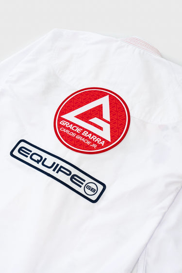 Close-up of the kimono jacket back showing the embroidered red Gracie Barra Carlos Gracie Jr. circular patch above a navy Equipe GB patch