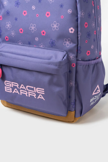 Close-up of Purple Sakura Backpack with floral pattern, Gracie Barra logo, front zippered pocket, and brown suede bottom panel